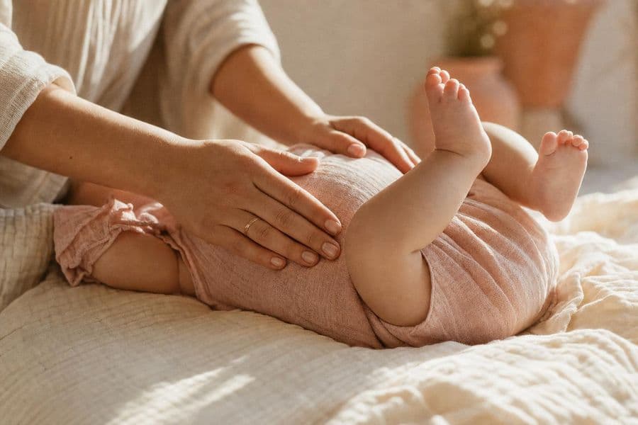 Elternhände liegen sanft auf dem Bauch eines Babys