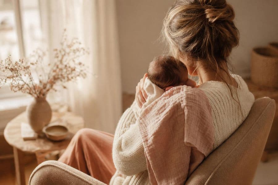 Stillende Mutter im Sessel am sonnigen Fenster